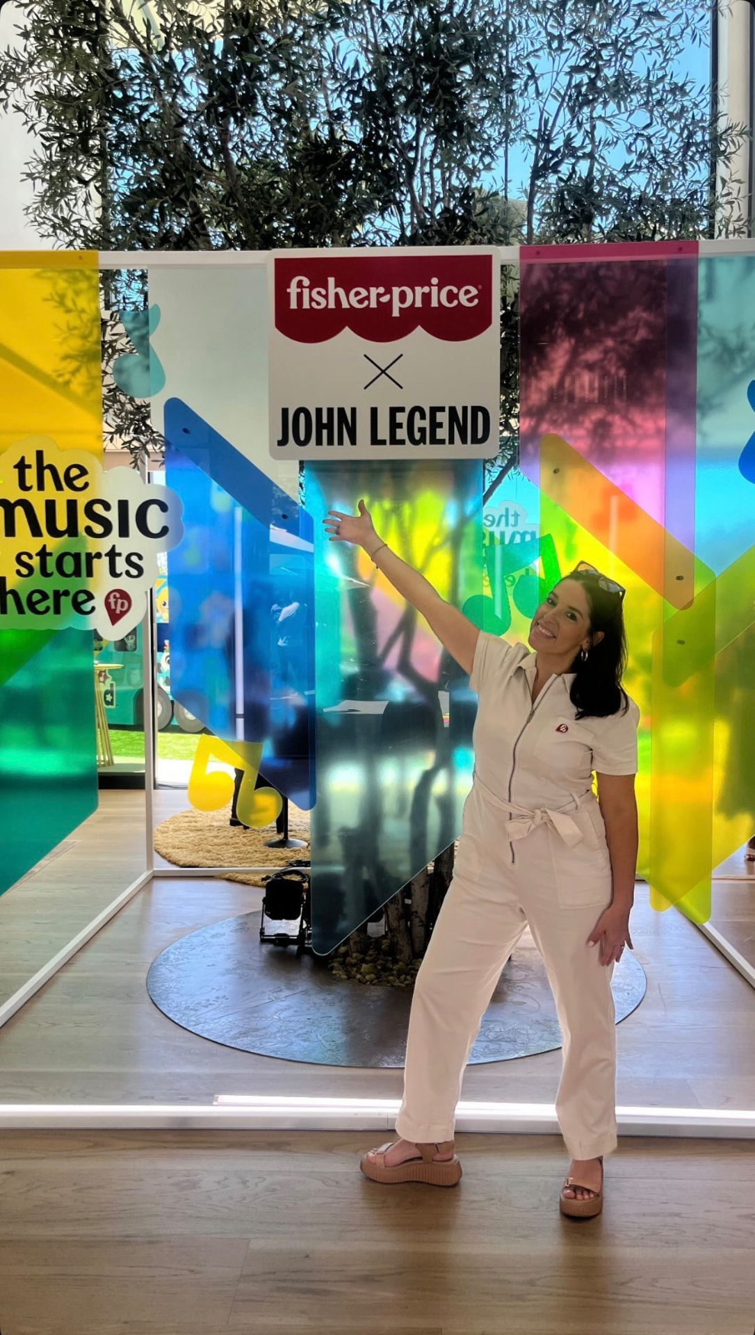 Florence Boza pointing to the Fisher-Price x John Legend partnership sign.